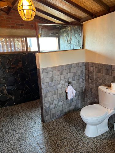 a bathroom with a toilet and a tiled wall at PINOKKIO B&B Restaurant in Jimbaran