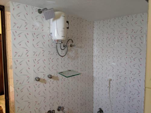 a bathroom with a shower with a white wall at Bluemoon Bungalow in Pondicherry