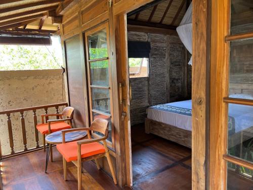 a room with a balcony with a bed and chairs at PINOKKIO B&B Restaurant in Jimbaran
