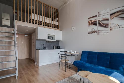 a living room with a blue couch and a kitchen at RentPlanet - Apartamenty Zarembowicza II in Wrocław