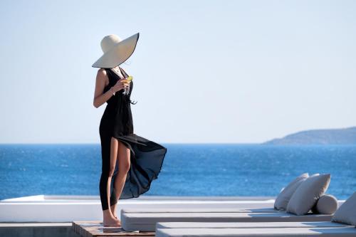 a woman in a black dress and hat standing on a raft at Manoula's Beach Mykonos Resort in Agios Ioannis Mykonos