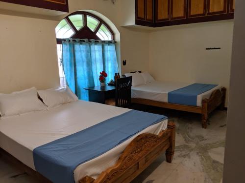 a bedroom with two beds and a window at Bluemoon Bungalow in Pondicherry