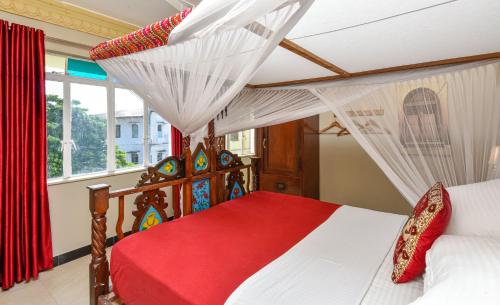 a bedroom with a canopy bed with a red blanket at Freddie Mercury Apartments in Zanzibar City