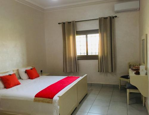 um quarto com uma cama com almofadas vermelhas e uma janela em Riad Nasma Souihla em Marrakech