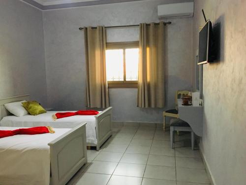 a small room with two beds and a window at Riad Nasma Souihla in Marrakech
