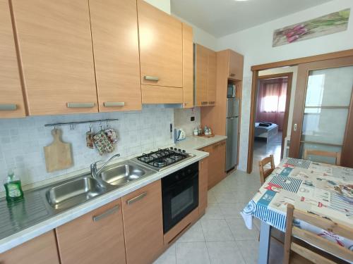 eine Küche mit Holzschränken, einer Spüle und einem Tisch in der Unterkunft Sofia Sweet Home in Corsico
