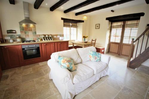 a living room with a white couch in a kitchen at Joli gîte pour 5 personnes : Chez Cherrie in Saint-Julien-de-Lampon