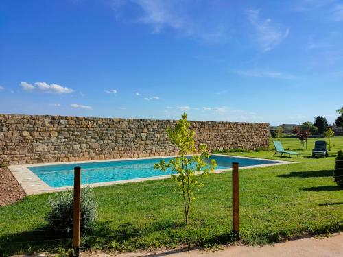 a swimming pool in a yard next to a stone wall at Casa Rural Torre Gil in Alcañiz