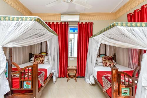 two beds in a room with red curtains at Tembo House Hotel in Zanzibar City