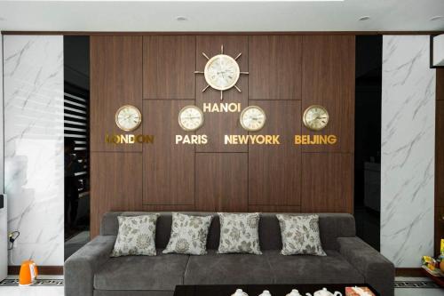 a couch in front of a wall with clocks on it at Minh Anh Hotel & Apartment in Hai Phong
