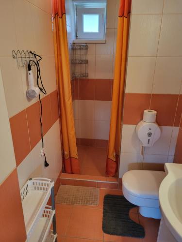 a bathroom with a toilet and a shower with orange curtains at Privat NIKA in Závažná Poruba