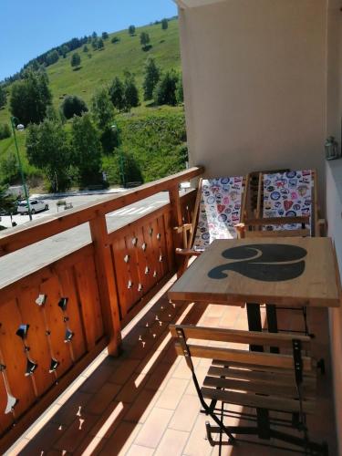 d'un balcon avec une table et un banc offrant une vue. dans l'établissement Appartement de 28 m2, centre station les 2 alpes, à Les Deux Alpes