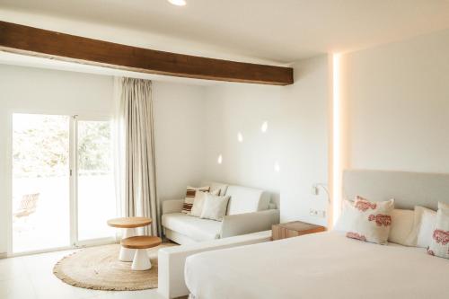 サン・アントニオ・ベイにあるHotel Boutique & Spa Las Mimosas Ibizaの白いベッドルーム(ベッド1台、ソファ付)