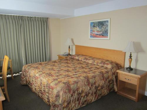 Habitación de hotel con cama, mesa y lámpara en Star Lodge, en Kamloops