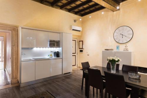 NSM 71 Via del Corso Luxury Home في روما: مطبخ وغرفة طعام مع طاولة وساعة