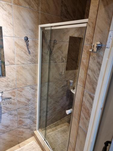 a shower with a glass door in a bathroom at Dolphins Self-Catering Accommodation in George