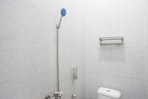 a white bathroom with a shower with a blue head at RedDoorz Syariah near Alun Alun Kajen in Pekalongan