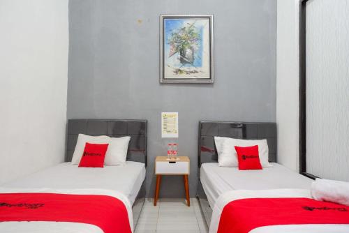 two beds in a room with red pillows at RedDoorz Syariah near Alun Alun Kajen in Pekalongan