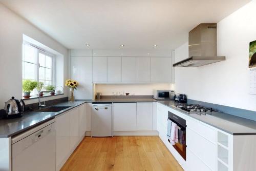 a white kitchen with white cabinets and a wooden floor at Lovely 2 bedroom flat overlooking Canary Wharf in London