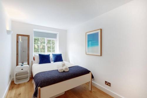 a bedroom with a bed with blue pillows and a window at Lovely 2 bedroom flat overlooking Canary Wharf in London