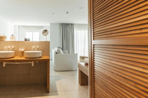 a bathroom with two sinks and a wooden door at Hotel Boutique & Spa Las Mimosas Ibiza in San Antonio Bay