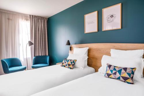 2 Betten in einem Hotelzimmer mit blauen Wänden in der Unterkunft Appart'City Confort St Quentin en Yvelines - Bois D'Arcy in Bois-dʼArcy
