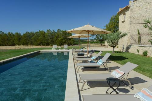 a pool with lounge chairs and an umbrella at La Bastide Neuve in Joucas