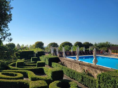 um jardim com uma piscina e guarda-sóis em Relais Sant'Uffizio Wellness & Spa em Cioccaro