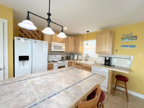 a kitchen with a white refrigerator and a table at Abby Sands Castle Home in Caplen