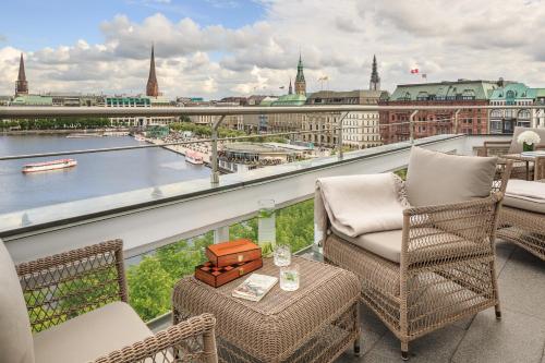a balcony with chairs and a view of a city at Fairmont Hotel Vier Jahreszeiten in Hamburg