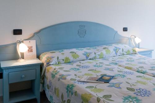 a bed with a blue headboard and a table with a lamp at Le Residenze di Santa Costanza - Mirto/Corbezzolo in San Vincenzo