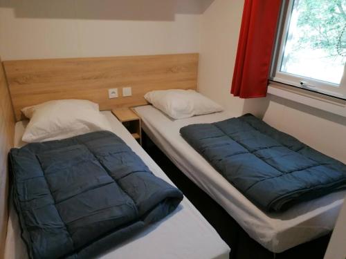 deux lits dans une petite pièce avec une fenêtre dans l'établissement MOBIL-HOME NEUF 6 PERSONNES réservation du samedi au samedi en juillet et août, à Urt
