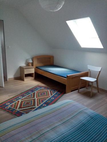 - une chambre avec un lit, une chaise et une lucarne dans l'établissement Logement indépendant, à Amboise