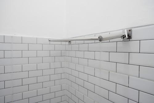 a white tiled bathroom with a white towel rack at RedDoorz @ Jalan Raya Baturaden 2 in Rempawah