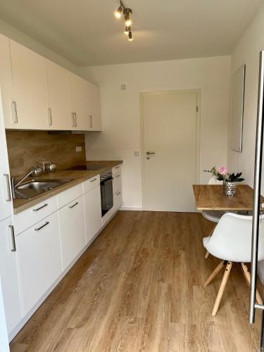 a kitchen with white cabinets and a wooden floor at Ferienwohnung mit Terrasse und Sauna in Ortenberg