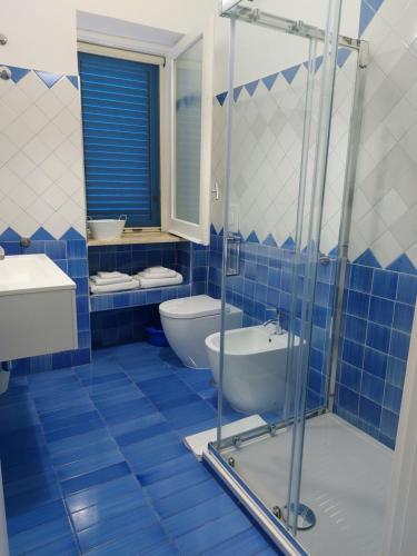 a blue tiled bathroom with a toilet and a sink at B&B Il Gabbiano in Cittadella del Capo