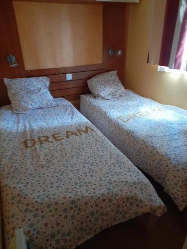 two beds sitting next to each other in a room at Mobil home camping les écureuils in Mimizan