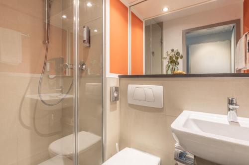 a bathroom with a shower and a toilet and a sink at Select Hotel Wiesbaden City in Wiesbaden