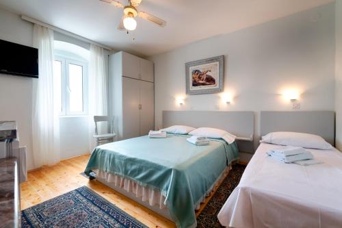 a bedroom with two beds and a ceiling fan at Apartments by the sea Komiza, Vis - 9703 in Komiža
