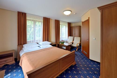 a bedroom with a bed and a desk and windows at Rehabilitation Centre & SPA Draugystės sanatorija in Druskininkai