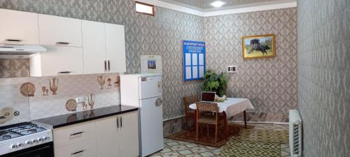 a kitchen with a table and a white refrigerator at LION Guest House in Bukhara