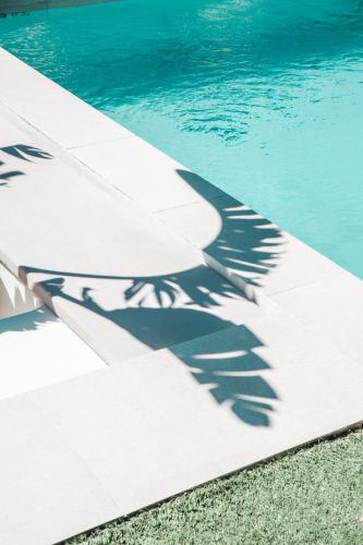 a shadow of a wing on the side of a swimming pool at Hotel Boutique & Spa Las Mimosas Ibiza in San Antonio Bay