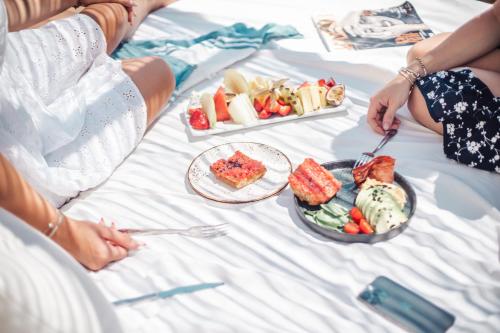 two people sitting on a bed with plates of food at Hotel Boutique & Spa Las Mimosas Ibiza in San Antonio Bay