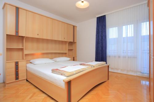 - une chambre avec un grand lit et des placards en bois dans l'établissement Apartments with a parking space Podstrana, Split - 10249, à Podstrana