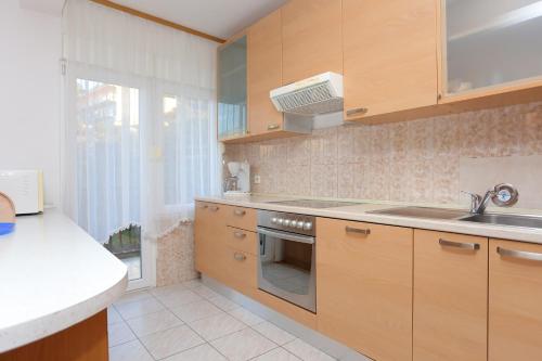 - une cuisine avec des placards en bois, un évier et une cuisinière dans l'établissement Apartments with a parking space Podstrana, Split - 10249, à Podstrana
