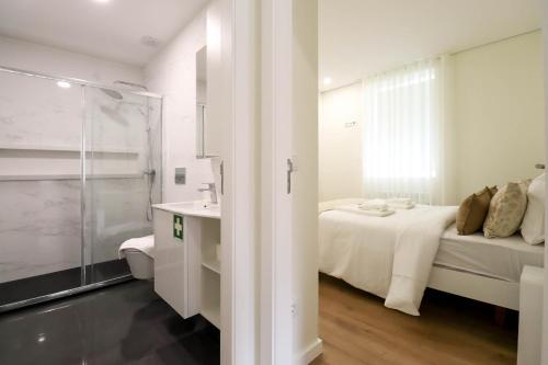 ein weißes Schlafzimmer mit einem Bett und einem Waschbecken in der Unterkunft Senhora da Agonia - Apartment in Ribeira in Viana do Castelo