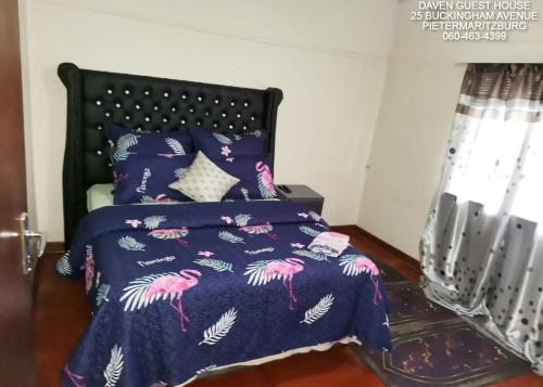 a bed with a purple bedspread with pink flamingos on it at Daven Guest House in Pietermaritzburg