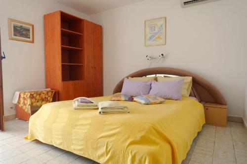 a bedroom with a yellow bed with two towels on it at Apartments with a parking space Orebic, Peljesac - 14834 in Orebić
