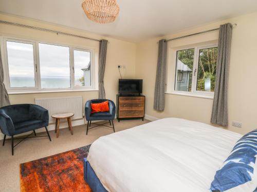 a bedroom with a bed and two chairs and a television at Ty Ni in New Quay