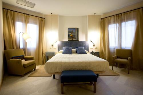 a bedroom with a large bed and two chairs at Hotel La Vida Spa in Aldeayuso